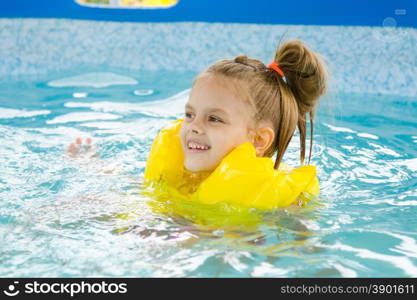 Happy girl swimming in the pool. Six year old girl Europeans bathed in a small suburban pool