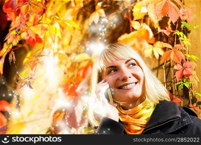 Happy girl talks to on the phone, abstract autumn background behind her