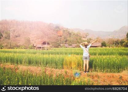 Happy girl traveler standing in flowers field, Summer vacation