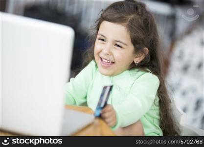 Happy girl using laptop and credit card to shop online at home