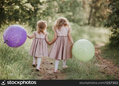 Happy girl with balloons. two beautiful little girls in the summer in a park with balloons in hands. two beautiful little girls in the summer in a park with balloons in hands. Happy girl with balloons.