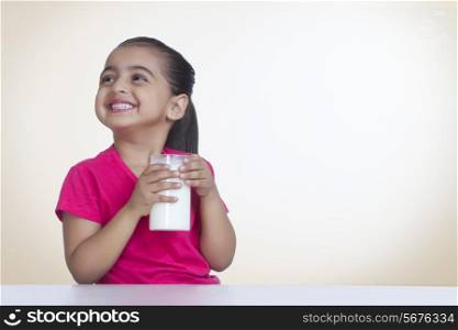 Happy girl with glass of milk against colored background