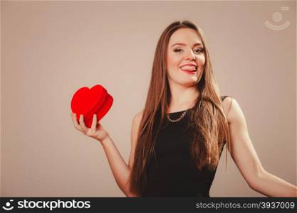 Happy girl with heart. Love help and charity concept. Young beauty happy long haired woman girl in black dress holding heart box gift in studio.