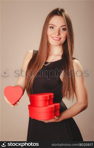 Happy girl with hearts. Love help and charity concept. Young beauty happy long haired woman girl in black dress holding hearts boxes gifts in studio.