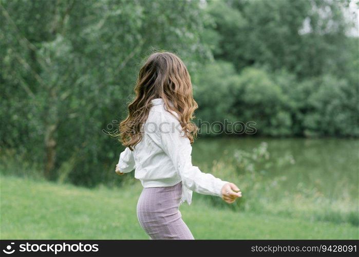 Happy girl with long wavy hair blowing in the wind in nature