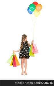 happy girl with shopping bags and balloons over white