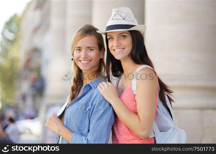 happy girlfriends walking through town during vacation