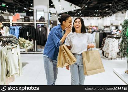 Happy girlfriends with purchases in bags, clothing store. Women shopping in fashion boutique, shopaholics, shoppers with purchase. Happy girlfriends with purchases in bags, shopping