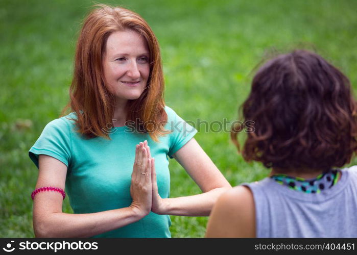 Happy girls doing yoga in the park on the grass. Healthy and Yoga Concept