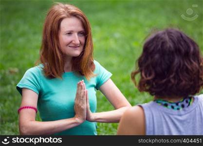 Happy girls doing yoga in the park on the grass. Healthy and Yoga Concept