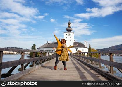 happy girls goes over the bridge to the castle ort, austria. family trip