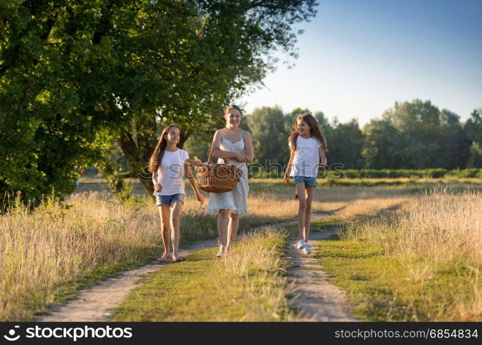 Happy girls walking with with mother on countryside road