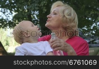 Happy grandmother with her grandchild having fun in summer park