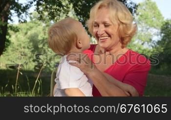 Happy grandmother with her grandchild having fun in summer park playing and smiling