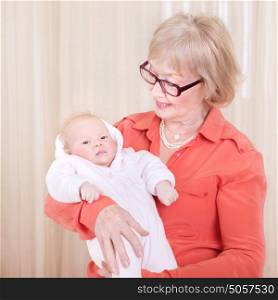 Happy granny holding newborn kid at home, enjoying sweet little grandchild, hugging with love, family happiness concept