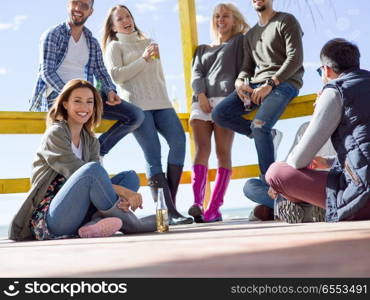 Happy Group Of Friends Hanging Out At Beach House having fun and drinking beer on autumn day. Group of friends having fun on autumn day at beach