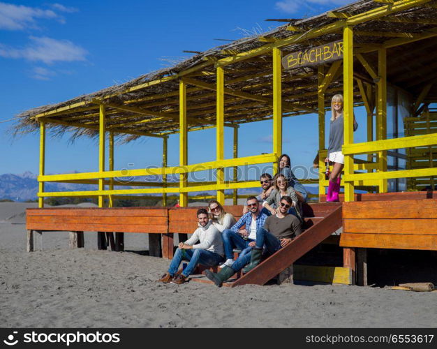 Happy Group Of Friends Hanging Out At Beach House having fun and drinking beer on autumn day. Group of friends having fun on autumn day at beach