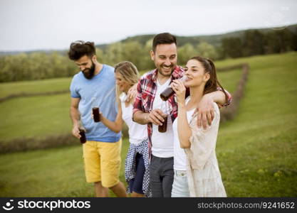 Happy group of friends with drink  having fun and smiling at nature by summer day