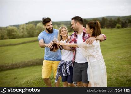 Happy group of friends with drink  having fun and smiling at nature by summer day