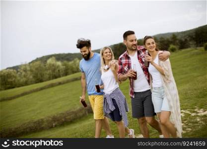 Happy group of friends with drink  having fun and smiling at nature by summer day
