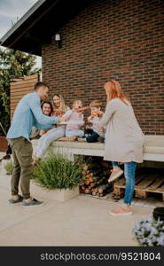 Happy group of young people and kids eating pizza in the house backyard