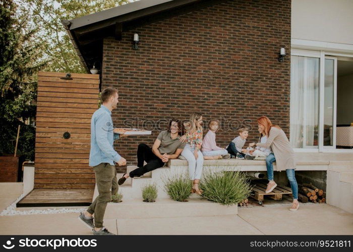 Happy group of young people and kids preparing for eating pizza in the house backyard