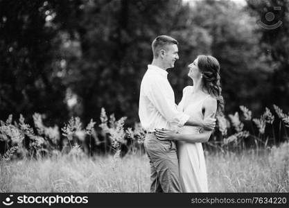 happy guy in a white shirt and a girl in a turquoise dress, the bride and groom are walking in the forest park