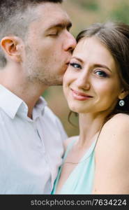 happy guy in a white shirt and a girl in a turquoise dress, the bride and groom are walking in the forest park