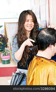 Happy hairdresser cutting hair in her salon