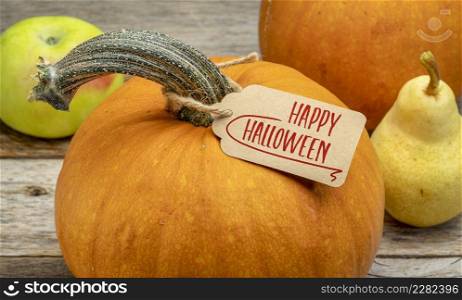 Happy Halloween - a pumpkin with a paper price tag against rustic barn wood, fall holiday concept and greeting card