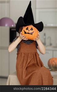 Happy halloween. Cute little girl in witch costume with carving pumpkin. Happy family preparing for Halloween. focus on the pumpkin.. Happy halloween. Cute little girl in witch costume with carving pumpkin. Happy family preparing for Halloween. focus on the pumpkin