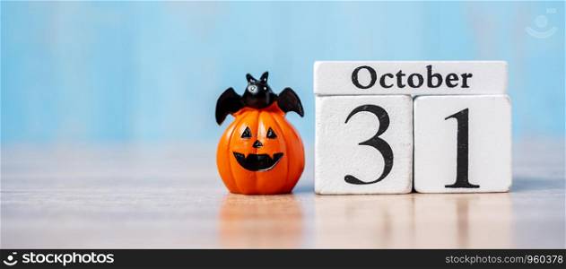 Happy Halloween day with 31 October calendar wood, jack o lantern pumpkin and bat decor with funny face on table background with copy space. Autumn season, Holiday and Trick and Treat concept