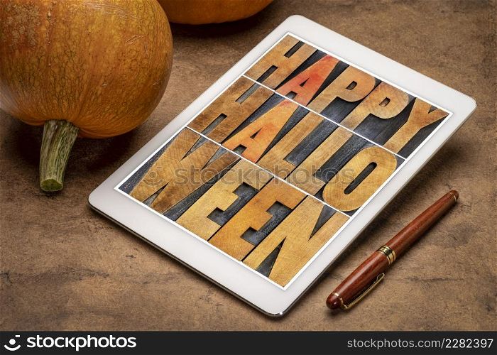 Happy Halloween greeting card - text in vintage grunge wood type printing blocks on a digital tablet with pumpkins
