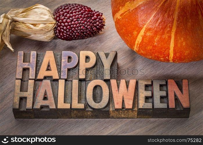 Happy Halloween greeting card - typography in vintage letterpress wood type with a pumpkin and strawberry corn