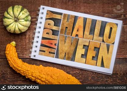Happy Halloween greeting card - word abstract in vintage grunge letterpress wood type in a sketchbook against rustic wood with decorative gourd