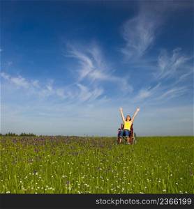 Happy handicapped woman on a wheelchair over a green meadow
