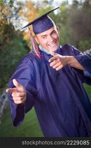 Happy Handsome Male Graduate in Cap and Gown Outside.