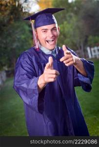 Happy Handsome Male Graduate in Cap and Gown Outside.