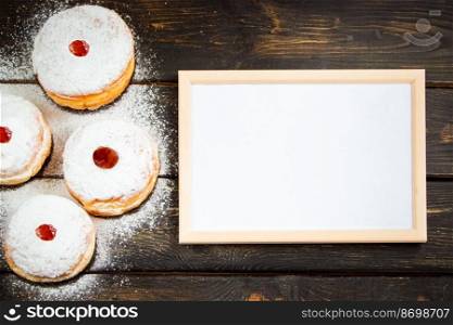 Happy Hanukkah. Empty frame for congratulations text and traditional dessert Sufganiyot on dark wooden background. Celebrating Jewish religious holiday.. Happy Hanukkah. Empty frame for congratulations text and traditional dessert Sufganiyot on dark wooden background. Celebrating Jewish holiday.
