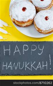 Happy Hanukkah. Jewish dessert Sufganiyot on yellow background. Symbols of religious Judaism holiday. Donuts, candles and gifts.. Happy Hanukkah. Jewish dessert Sufganiyot on yellow background. Symbols of religious Judaism holiday. Donuts, candles and gift.