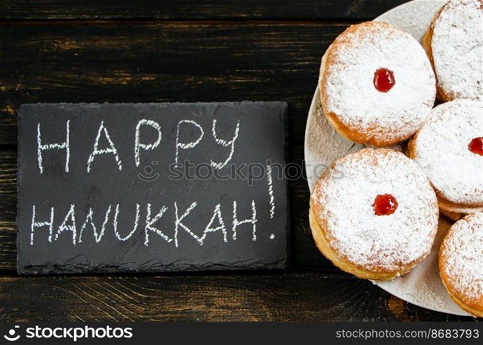 Happy Hanukkah. Traditional dessert Sufganiyot on dark wooden background. Donuts, candles and gifts. Celebrating Jewish religious holiday.. Happy Hanukkah. Traditional dessert Sufganiyot on dark wooden background. Donuts, candles and gifts. Celebrating Jewish holiday.
