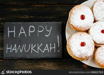 Happy Hanukkah. Traditional dessert Sufganiyot on dark wooden background. Donuts, candles and gifts. Celebrating Jewish religious holiday.. Happy Hanukkah. Traditional dessert Sufganiyot on dark wooden background. Donuts, candles and gifts. Celebrating Jewish holiday.