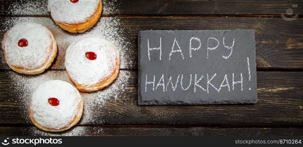 Happy Hanukkah. Traditional dessert Sufganiyot on dark wooden background. Donuts, candles and gifts. Celebrating Jewish religious holiday. Banner format.. Happy Hanukkah. Traditional dessert Sufganiyot on dark wooden background. Donuts, candles and gifts. Celebrating Jewish holiday.
