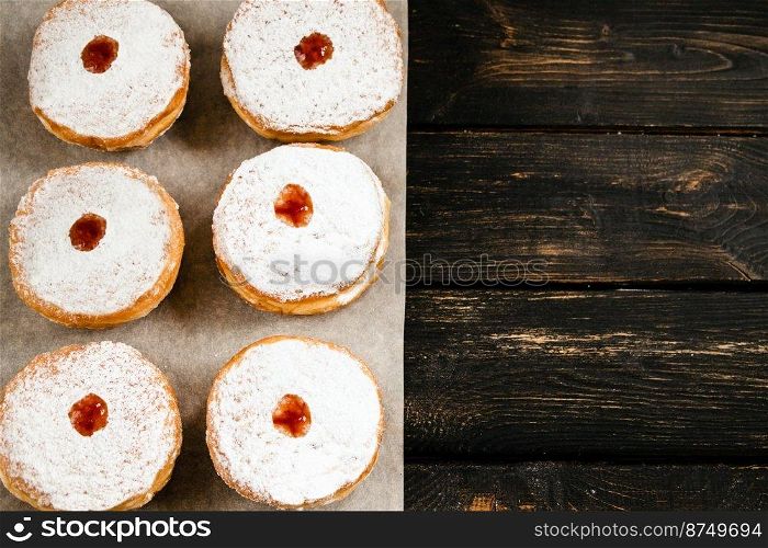 Happy Hanukkah. Traditional dessert Sufganiyot on dark wooden background. Donuts, candles and gifts. Celebrating Jewish religious holiday. Copy space.. Happy Hanukkah. Traditional dessert Sufganiyot on dark wooden background. Donuts, candles and gifts. Celebrating Jewish holiday.