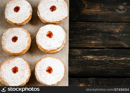 Happy Hanukkah. Traditional dessert Sufganiyot on dark wooden background. Donuts, candles and gifts. Celebrating Jewish religious holiday. Copy space.. Happy Hanukkah. Traditional dessert Sufganiyot on dark wooden background. Donuts, candles and gifts. Celebrating Jewish holiday.