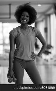 happy healthy african american woman working out in a crossfit gym on weight loss with dumbbells