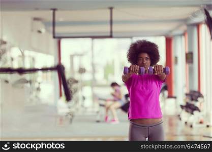 happy healthy african american woman working out in a crossfit gym on weight loss with dumbbells. woman working out in a crossfit gym with dumbbells