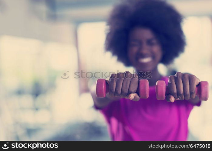 happy healthy african american woman working out in a crossfit gym on weight loss with dumbbells. woman working out in a crossfit gym with dumbbells