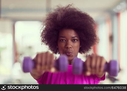 happy healthy african american woman working out in a crossfit gym on weight loss with dumbbells. woman working out in a crossfit gym with dumbbells