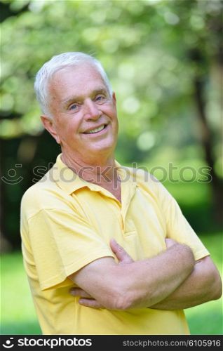 happy healthy and fit elderly man portrait in green background park